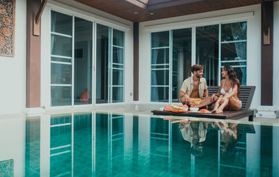 Couple sitting by swimming pool