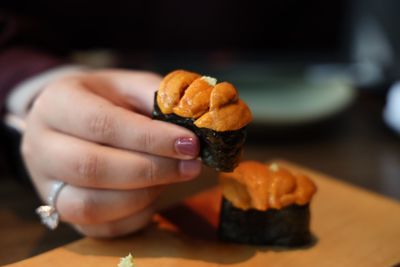 Close-up of hand holding uni sushi