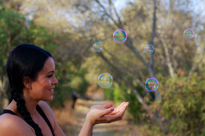 Close-up of smiling woman looking at bubbles