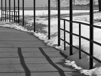 Shadow of railing on footpath by sea