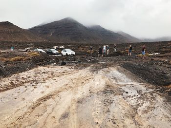 People on land against mountain range