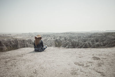 Man sitting on land against clear sky