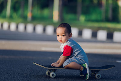 Portrait of cute boy sitting in park. boy sitting on skateboard