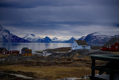 Houses at lakeshore against cloudy sky during winter