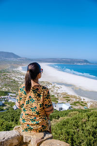 Side view of woman looking at sea against sky