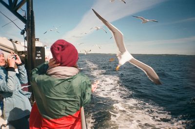 Rear view of people in sea against sky