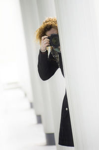 Woman photographing with digital camera in corridor