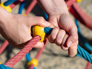 Iron jointed point of ropes in children spider web, hand holding rope while climbing a wooden wall.