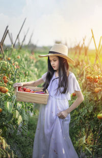 Young woman in hat standing on field