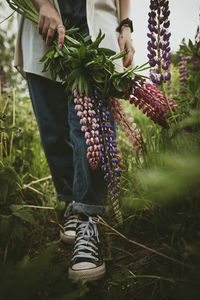 Teenage girl with lupin flowers walking on field