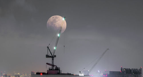 Low angle view of illuminated commercial dock against sky at night