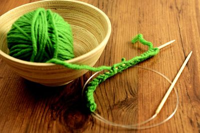 Close-up of knitting needle and wool in bowl on table