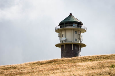 Lighthouse on field against sky