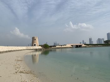 Buildings by sea against sky