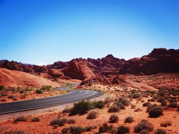 Mountain road against clear blue sky on sunny day