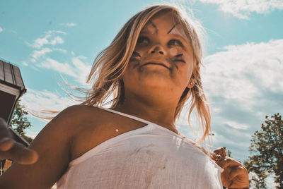 Low angle portrait of woman against sky