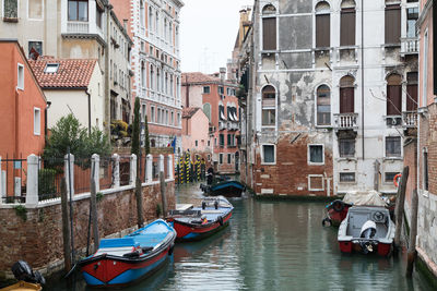 Boats moored in canal amidst buildings in city