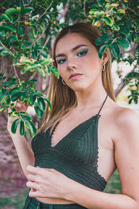 Portrait of young woman standing against plants