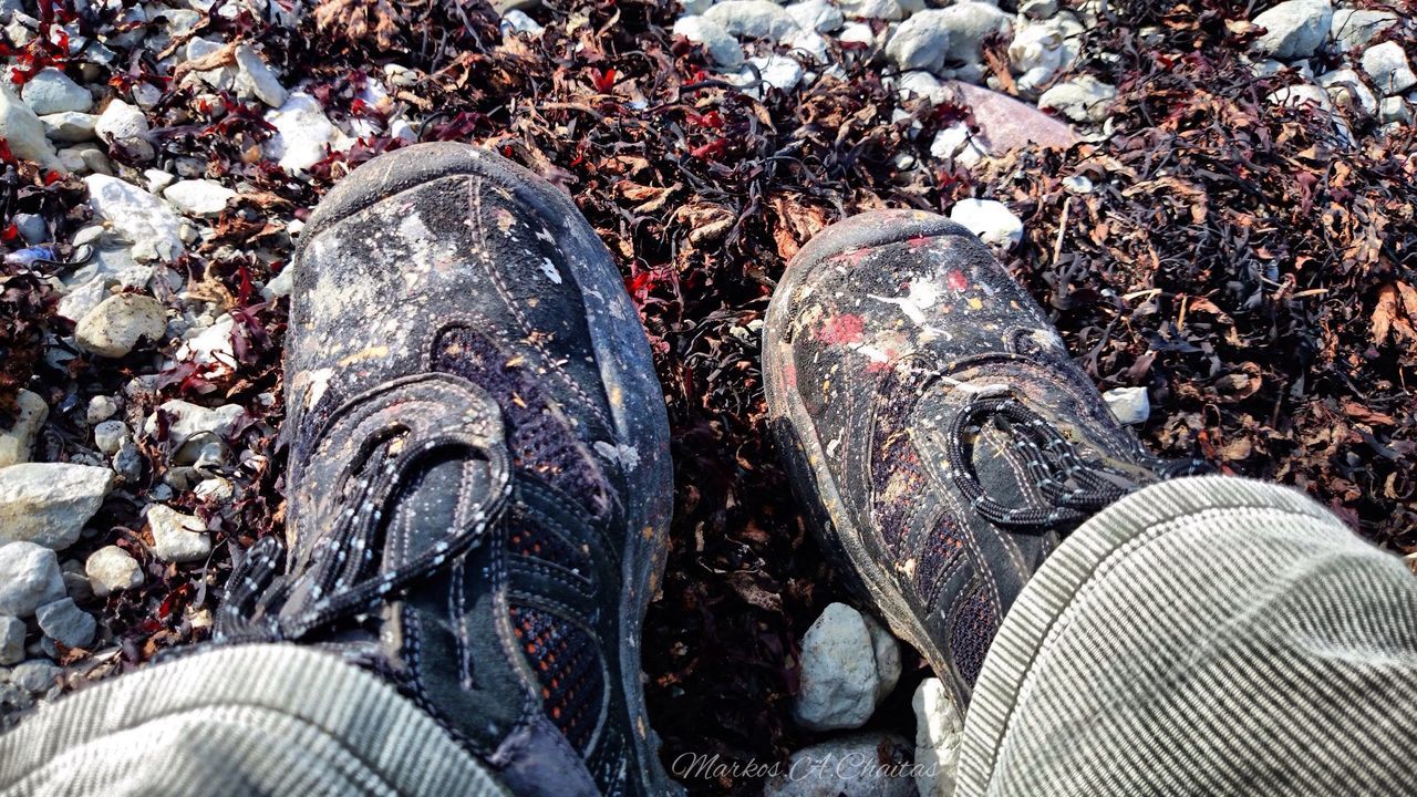 high angle view, shoe, low section, close-up, field, outdoors, stone - object, personal perspective, footwear, day, person, sunlight, part of, directly above, street, pair, ground, rock - object, covering, abandoned