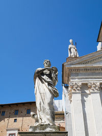 Low angle view of statue against building against clear blue sky