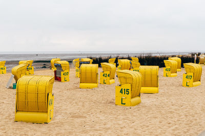 Hooded chairs on beach against sky
