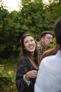 Portrait of smiling friends standing against trees