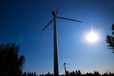 Low angle view of wind turbines against sky