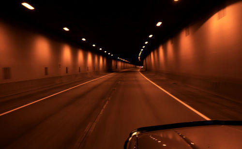 Cropped image of car moving in illuminated tunnel