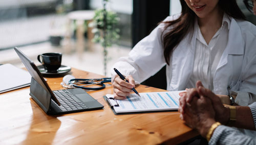 Midsection of businesswoman working on table