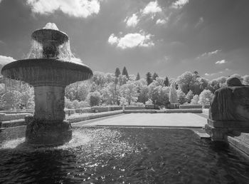 Fountain by lake against sky