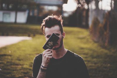 Portrait of woman holding camera while standing on mobile phone