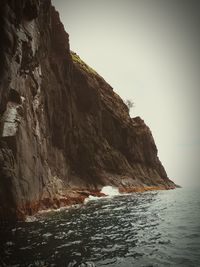 Rock formations by sea against clear sky