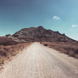 Road leading towards mountain against sky