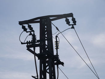 Low angle view of silhouette electricity pylon against sky