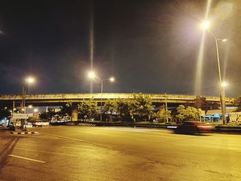 Illuminated street against sky at night