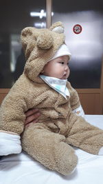 Close-up of cute baby boy in warm clothing sitting at home