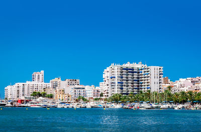 Sea by city against clear blue sky