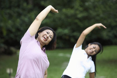 Smiling friends exercising at park