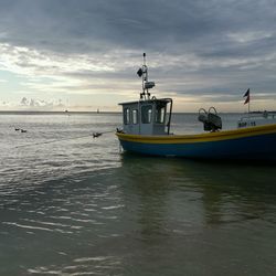 Boat moored in sea against sky during sunset