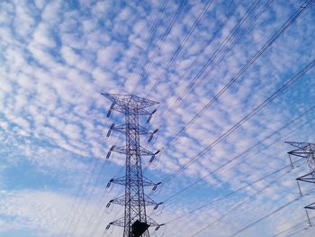 Low angle view of electricity pylon against cloudy sky