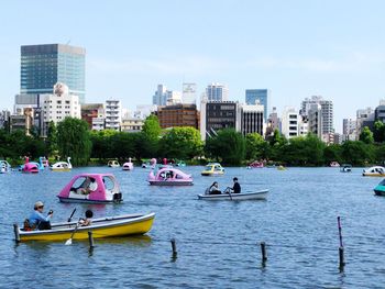 Boats in river by city against clear sky