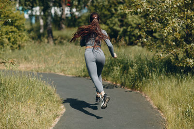 Rear view of woman running on road against trees