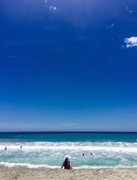 People on beach against blue sky