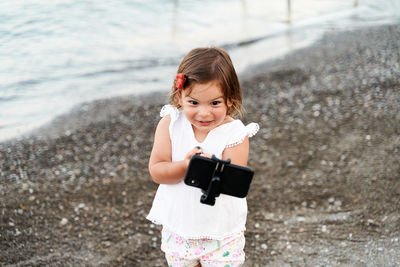 Close-up of girl doing selfie with mobile at beach