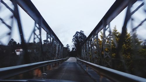 Empty footbridge against sky during winter