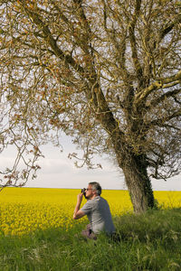 Man photographing through camera while crouching at farm