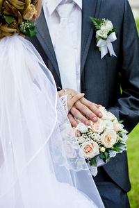 Midsection of couple holding flower bouquet