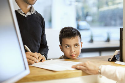 Family filling papers at reception counter in orthopedic clinic