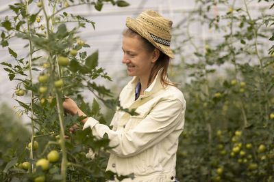 Young woman working as vegetable grower or farmer in a greenhouse