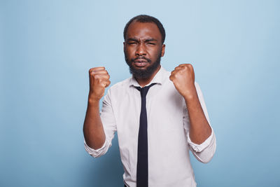 Portrait of young man standing against blue background